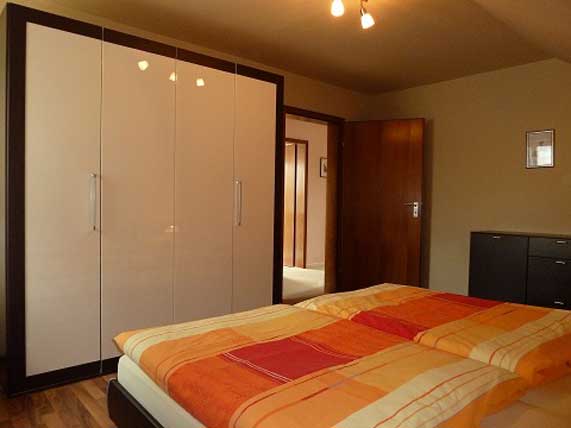 Das Schlafzimmer ist mit einem Doppelbett, einem großen Kleiderschrank und einer Kommode ausgestattet.
